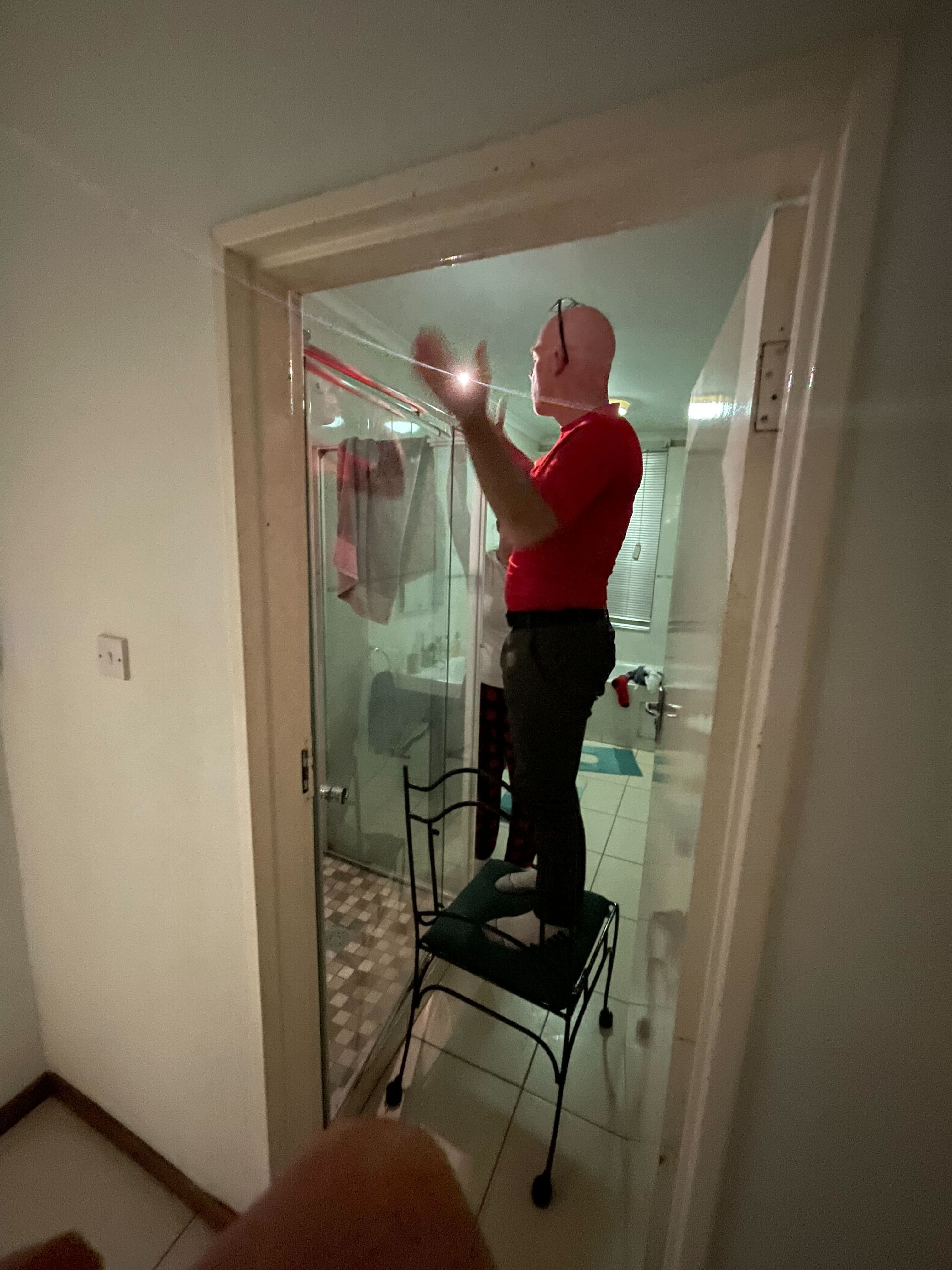 Rob standing on a chair and tussling with the shower door