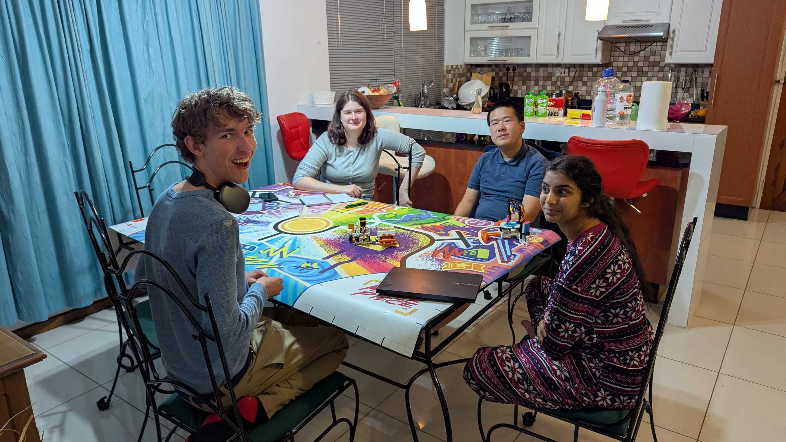 Group photo at a table with an FLL MASTERPIECE mat and mission modules